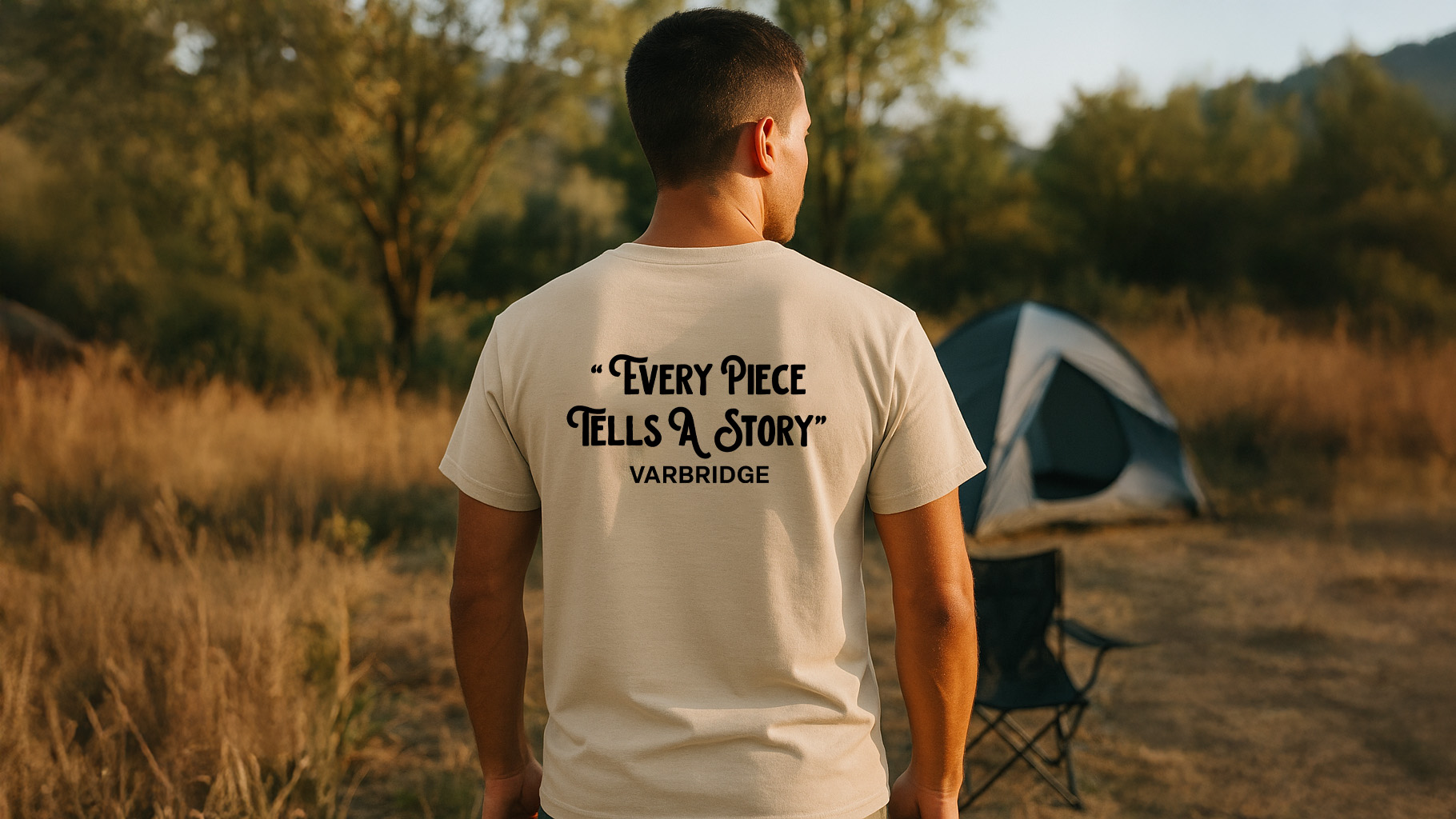 Man standing near a tent in the outdoors wearing the Varbridge “Every Piece Tells a Story” natural tee with bold slogan print - rugged cotton t-shirt designed for makers, grafters, and storytellers.