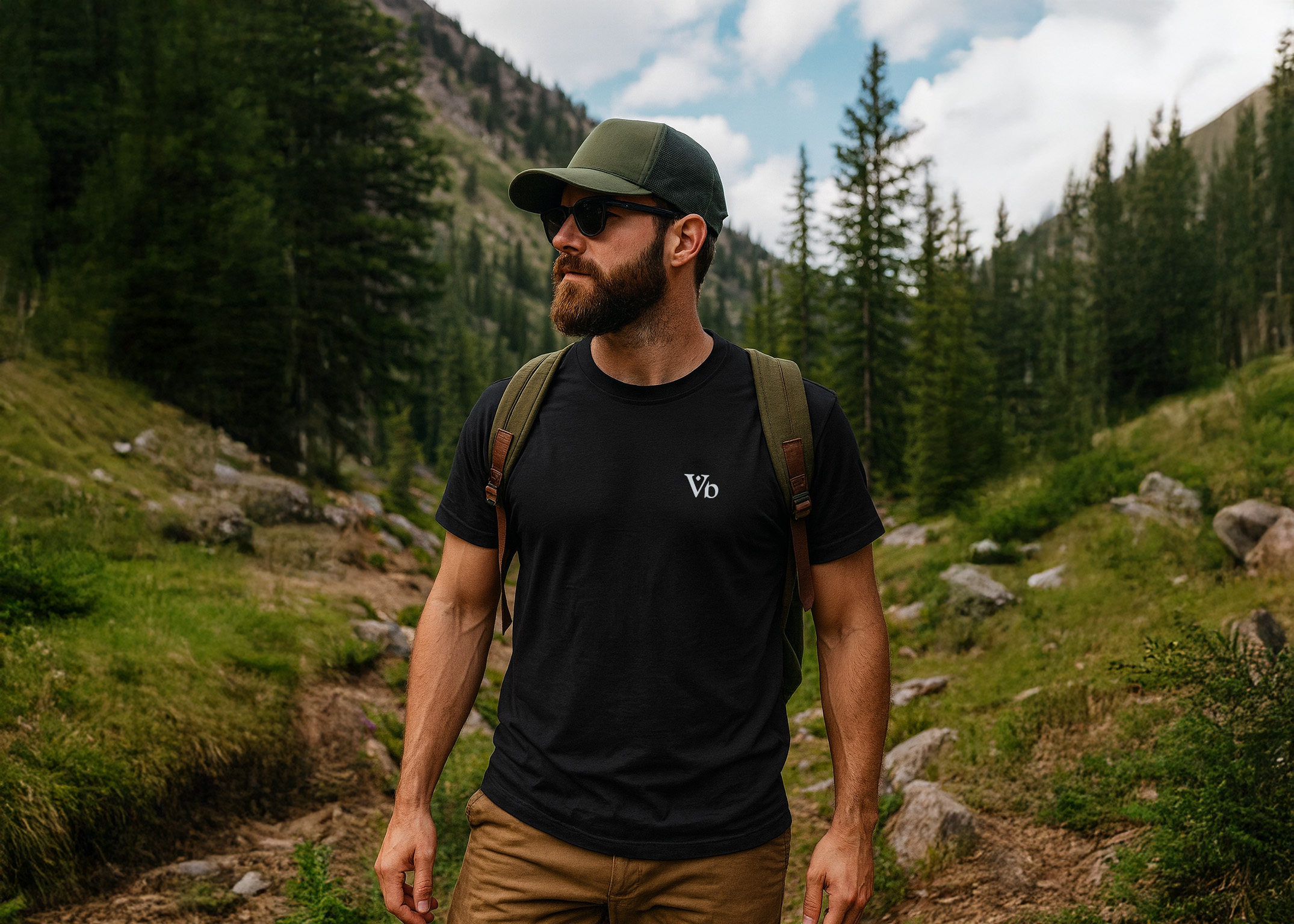 Man hiking through a forested mountain trail wearing the Varbridge classic black tee with minimalist Vb chest logo - rugged everyday t-shirt for work, travel, and adventure.