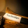 Varbridge Longhorn Pendant packaging box set against layered wood and volcanic rock, with soft, warm lighting and a dark backdrop.