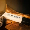 Varbridge Wayfinder Pendant packaging box resting on layered wood and volcanic rock, with a dark background and warm directional lighting.