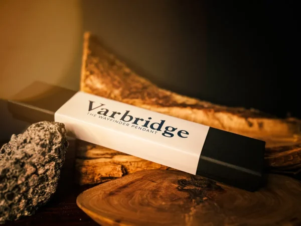 Varbridge Wayfinder Pendant packaging box resting on layered wood and volcanic rock, with a dark background and warm directional lighting.
