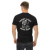 Man wearing a black t-shirt with a white graphic on the back showing a skeleton hiker with a backpack, lantern, and walking stick standing on rocky ground, surrounded by the phrase “CARRY LIGHT MOVE HARD.”