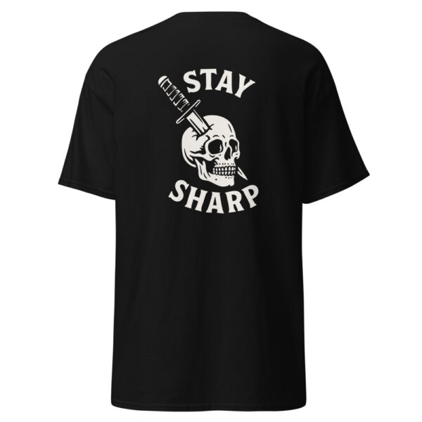 Back view of a black t-shirt with a white graphic design featuring a skull impaled by a tactical knife and the phrase “STAY SHARP” in bold curved text above and below the illustration.